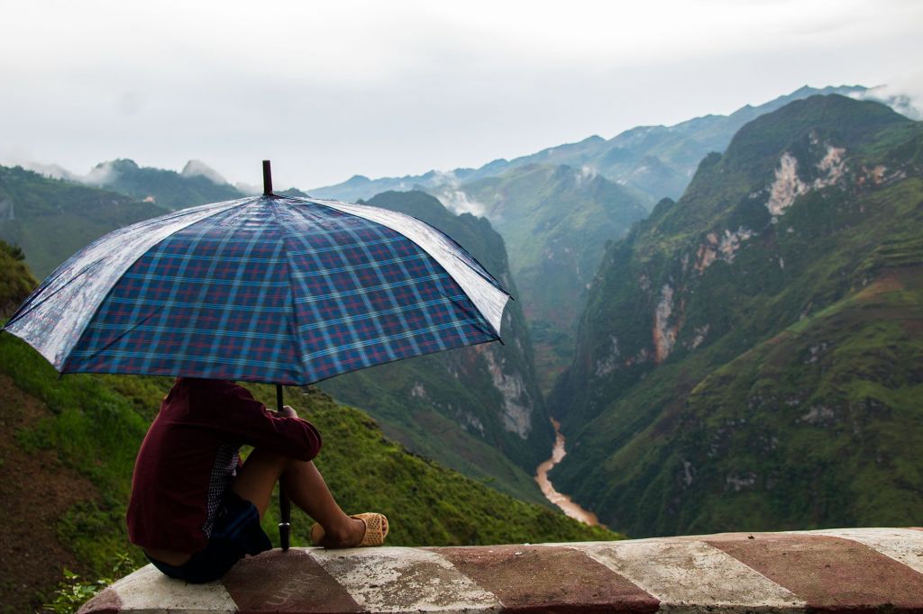Đứa trẻ ngồi một mình trên đèo Mã Pì Leng, ngắm dòng sông Nho Quế và hẻm Tu Sản